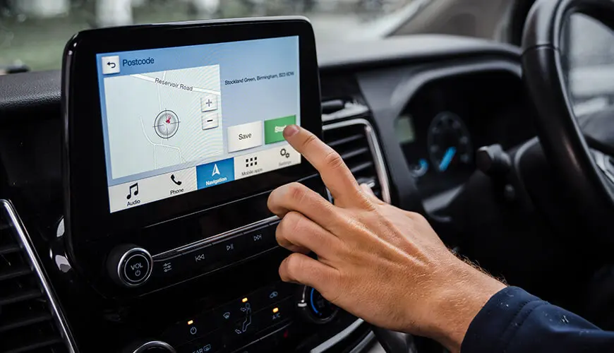 Close up of a hand touching a touch screen in a car with a map